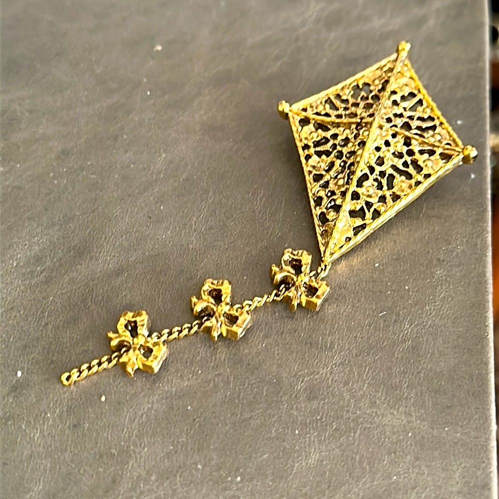 Filigree gold tone kite with ribbons bows on the tail brooch